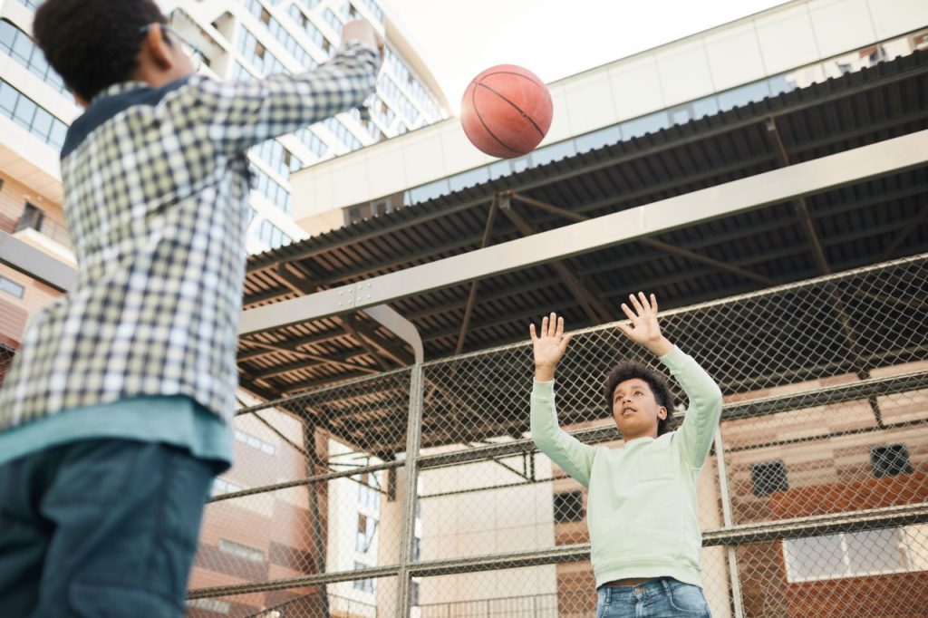 Two boys enjoying a game of basketball on an urban playground, showcasing youthful energy and sportsmanship.